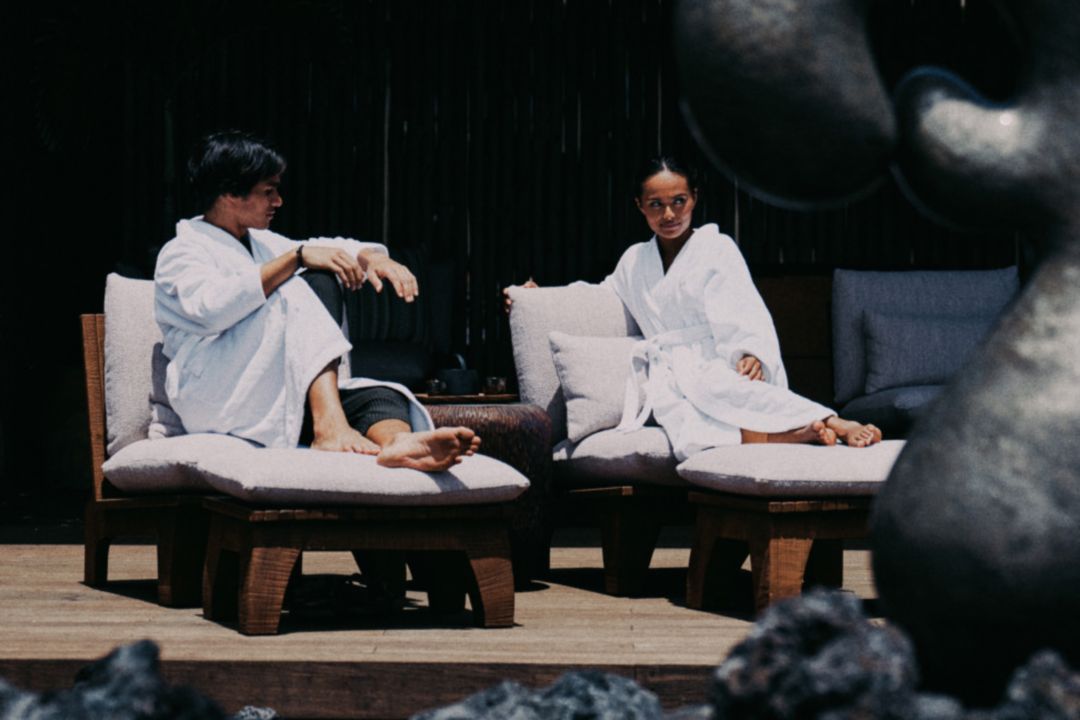 A couple in white robes relaxing on lounge  chairs at a spa in Hawaii.